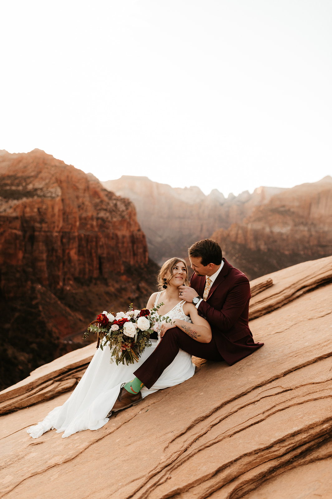 couple embracing while sitting on a cliff in Zion National Park