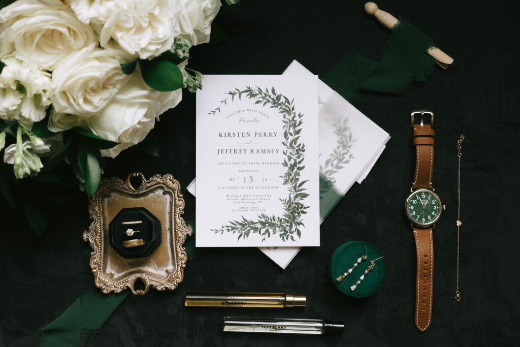 Detail flatlay with white florals and invites, green and black accents
