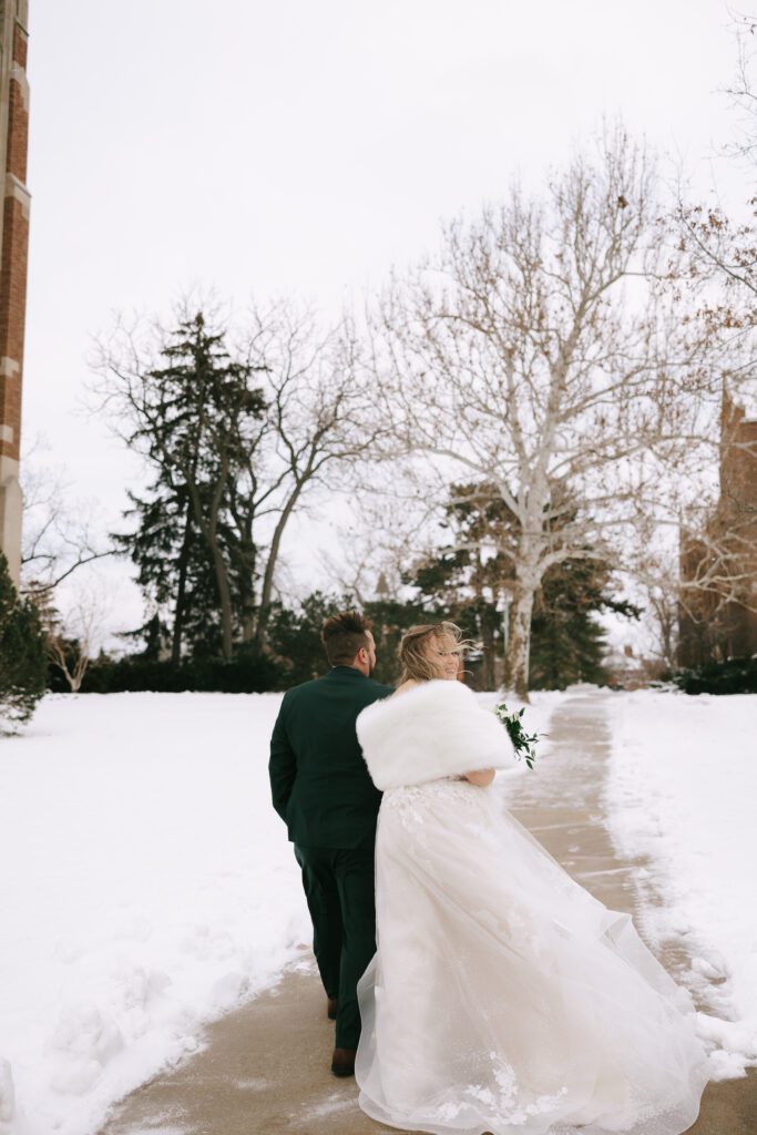 Kirsten and Jeff walk near Beaumont tower on Michigan State University's Campus on their wedding day