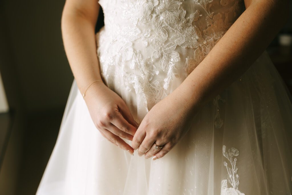 A closeup of Kirstens dress and hands before her Michigan wedding